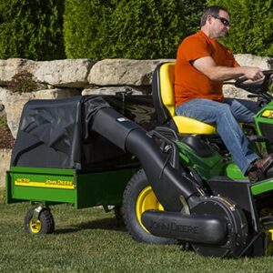 Man riding a mower with a cart attached