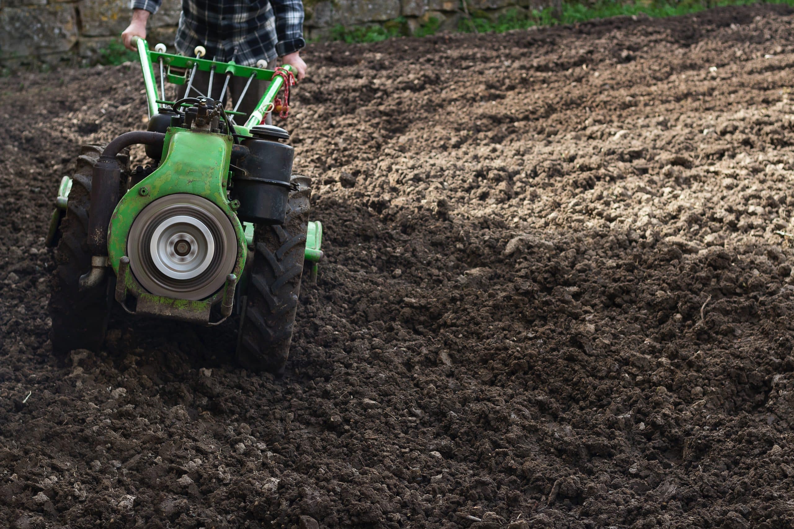 A tiller working through a field of soil. 